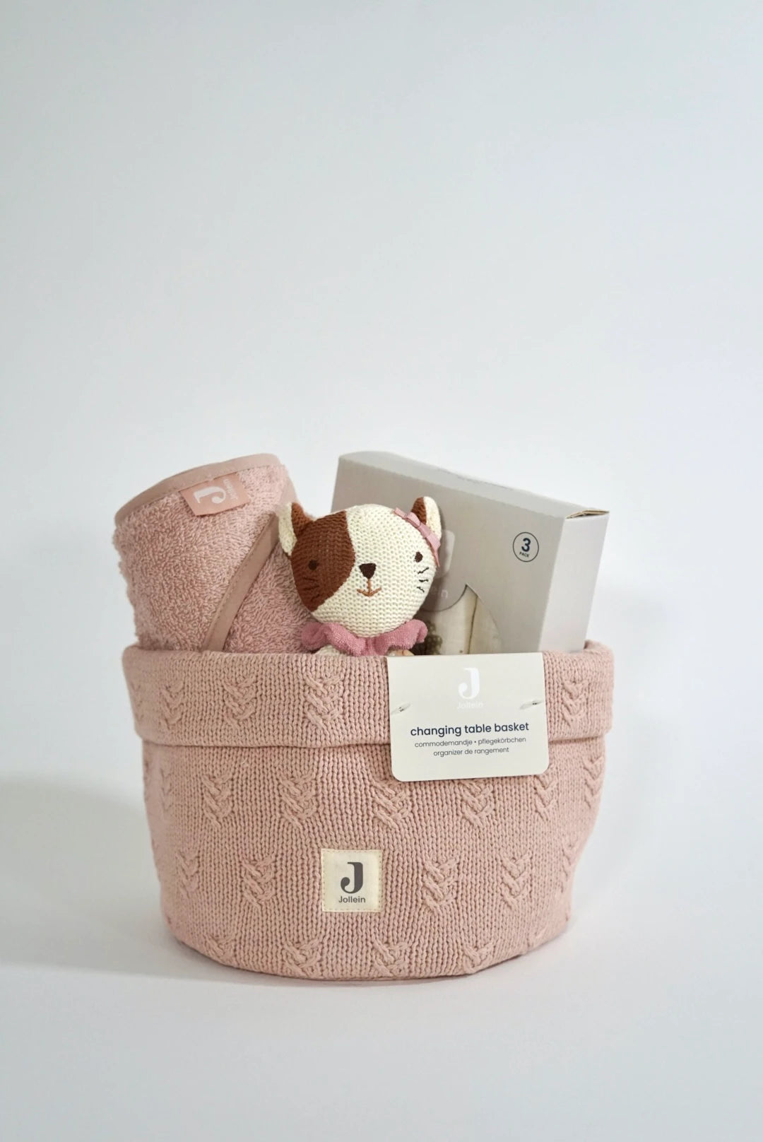 Eine geschenkbox für werdende eltern in rosa Style. Ein rosa Strick Pflegekorb mit einem rosa Kapuzenhandtuch aus Frottee Stoff, ein 3er Set Mulltücher (mit süßem schlichten tiny park Aufdruck) und ein Beißring Katze.
